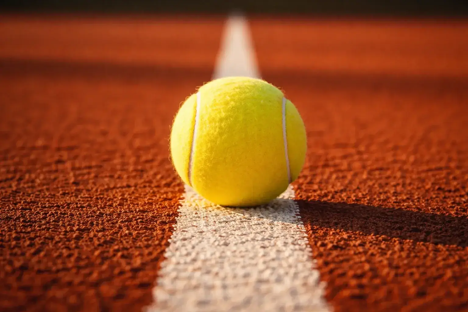 Tennisball auf weißer Linie eines Sandplatzes